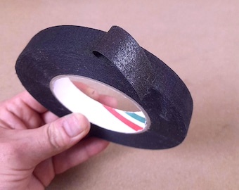 以下が含まれることがあります： 表面がテクスチャー加工された黒い布製テープのロール。上部に「5-20mm x 50meters」という文字が印刷されています。テープは白いプラスチック製の芯に巻かれており、スプールの内側の縁には赤と緑のストライプが見えます。