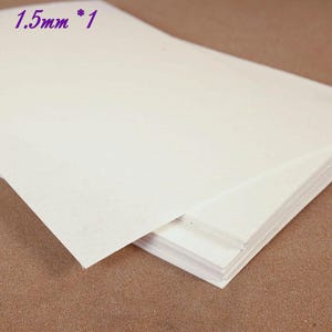 May include: A stack of off-white paper sheets. The text "1.5mm * 1" is in the upper left corner. The paper appears to be a light cream color. The sheets are stacked on top of each other.