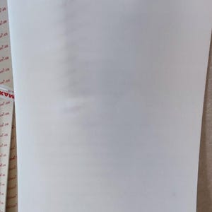 Puede incluir: Una gran l&aacute;mina rectangular de material de espuma blanca. La espuma parece lisa y s&oacute;lida, con una ligera curvatura en el borde derecho. La l&aacute;mina est&aacute; colocada verticalmente, ocupando la mayor parte del encuadre.