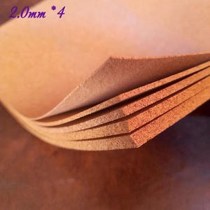 Può includere: Primo piano di diversi fogli di pelle color cuoio. I bordi della pelle sono visibili, mostrando lo spessore del materiale. Il testo "2,0 mm * 4" è nell'angolo in alto a sinistra. La pelle sembra nuova e inutilizzata.