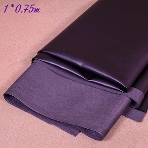 May include: A folded piece of dark purple leather fabric, with a visible rough underside. The fabric is approximately 0.75 meters in length. The image shows the texture and color variations of the material, suitable for crafting or upholstery projects.