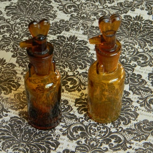 Mooie oud amberbruine glazen apothekersfles met ongewone geslepen glazen stop. Twee beschikbaar. Individueel verkocht.