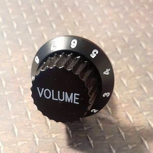 May include: Black volume knob with white numbers 2 to 9 and the word "VOLUME" printed on the front.