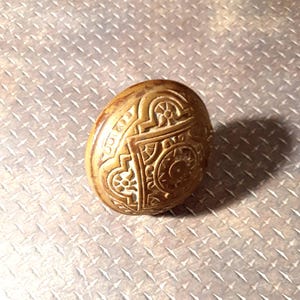 Peut inclure: Une poignée de porte en laiton vintage avec un design complexe et orné. La poignée est ronde et présente un motif surélevé et détaillé.