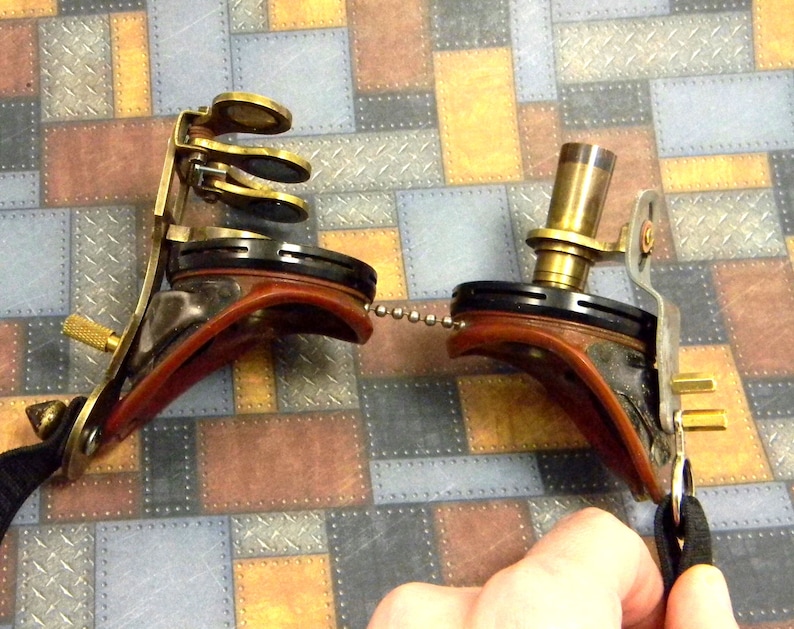 May include: A steampunk-style brass and leather eye patch with a chain and a lens. The eye patch has a brown leather strap and a brass frame with a round lens. The lens is attached to the frame with a chain.