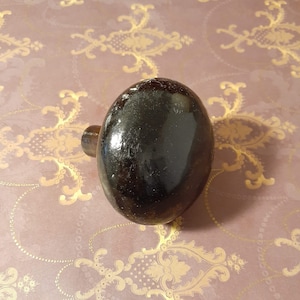 May include: A black, round door knob with a shiny finish.