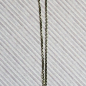 May include: A silver chain necklace with a gold gear pendant.