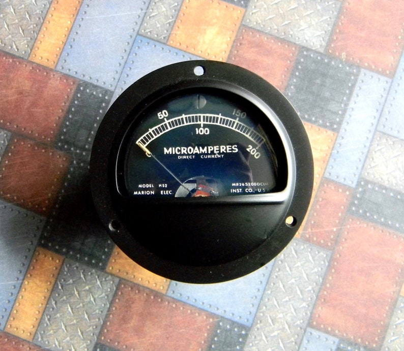 Puede incluir: Un medidor anal&oacute;gico circular negro con una cara blanca y una aguja negra. El medidor lee "MICROAMPERES DIRECT CURRENT" y tiene marcas de 0 a 200. El medidor est&aacute; etiquetado "MODEL HSS MARION ELEC MP745300DCU INST. CO-US".