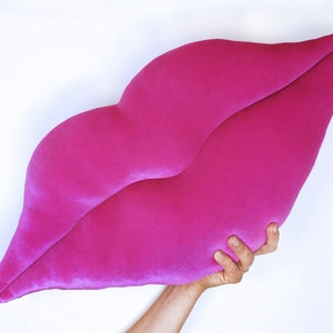 May include: A large, bright pink, plush pillow shaped like a pair of lips.
