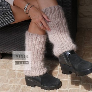 Puede incluir: Un par de polainas de pelo rosa claro con una bota de ante negro. Las polainas son de punto y tienen una textura suave y esponjosa. Las botas tienen un tacón grueso y una puntera redonda.