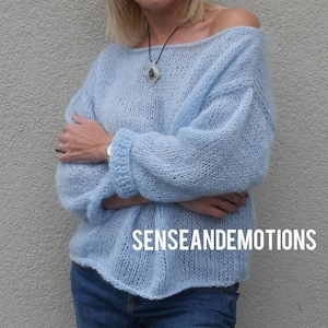Op de afbeelding: Een lichtblauwe oversized gebreide trui met een losse pasvorm en lange mouwen. De trui heeft een brede halslijn en een ontspannen, casual stijl. De tekst "SENSEANDEMOTIONS" is zichtbaar aan de onderkant van de trui.