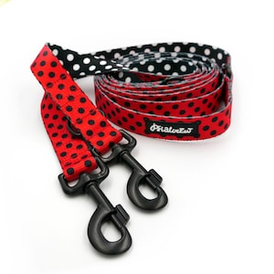 May include: A red and black polka dot dog lead with black metal clasps. The lead is rolled up and has a matching handle. The brand name "Psialurew" is printed on the lead.