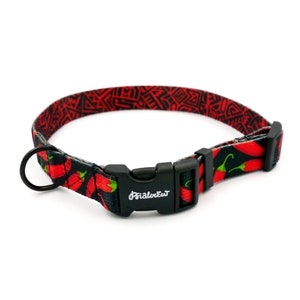 Puede incluir: Un collar de perro rojo y negro con un patr&oacute;n de chiles y una hebilla de pl&aacute;stico negro. La hebilla tiene la palabra "PrimalPet" impresa en ella.