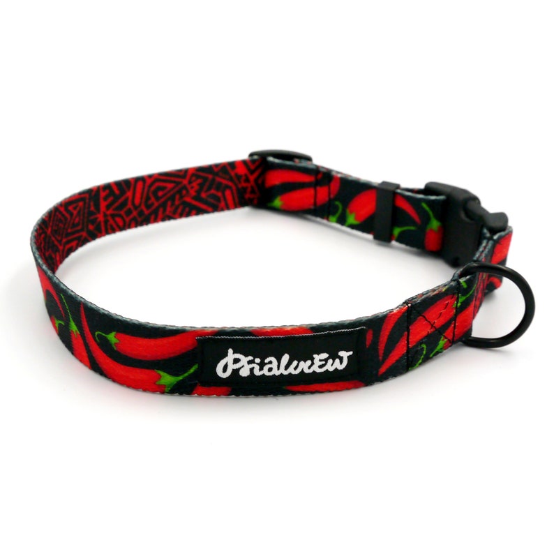 Puede incluir: Un collar de perro negro con un patr&oacute;n de chile rojo y el texto "Primal Pet" en blanco.