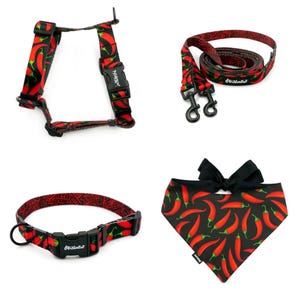 Puede incluir: Un conjunto de arn&eacute;s, correa, collar y bandana para perro con estampado de chiles rojos. El conjunto presenta un fondo negro con chiles rojos impresos en &eacute;l. El nombre de la marca "Pawsitive" est&aacute; impreso en el arn&eacute;s, la correa y el collar.