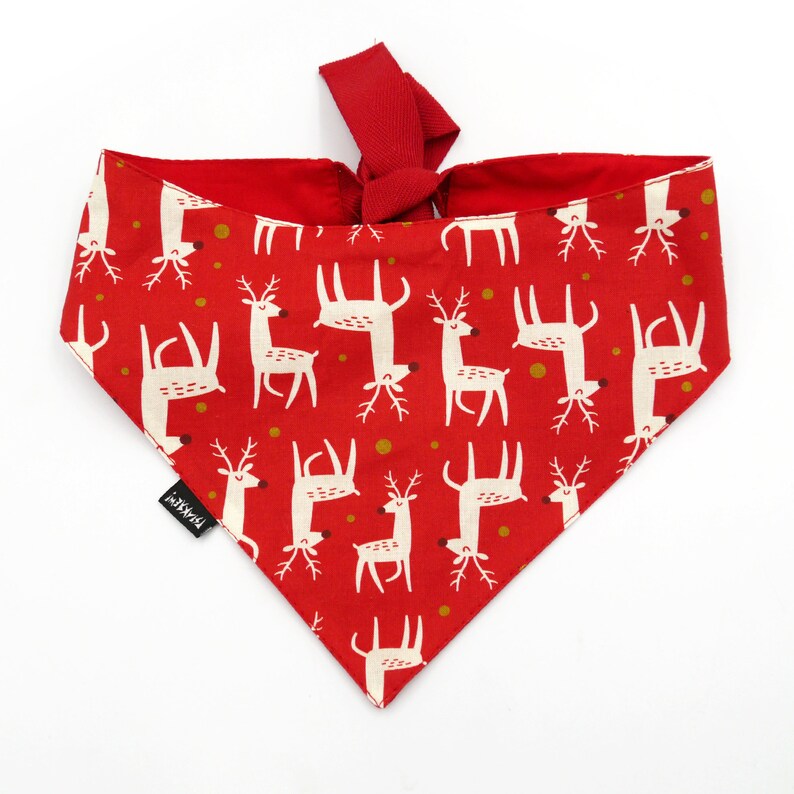 May include: Red bandana with a white reindeer pattern. The bandana has a tie at the top and is made of cotton.