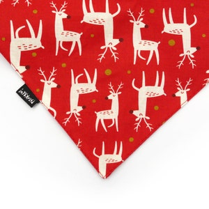 May include: Red fabric with a white reindeer pattern. The fabric has gold dots and the text "Pawsitive" in black.