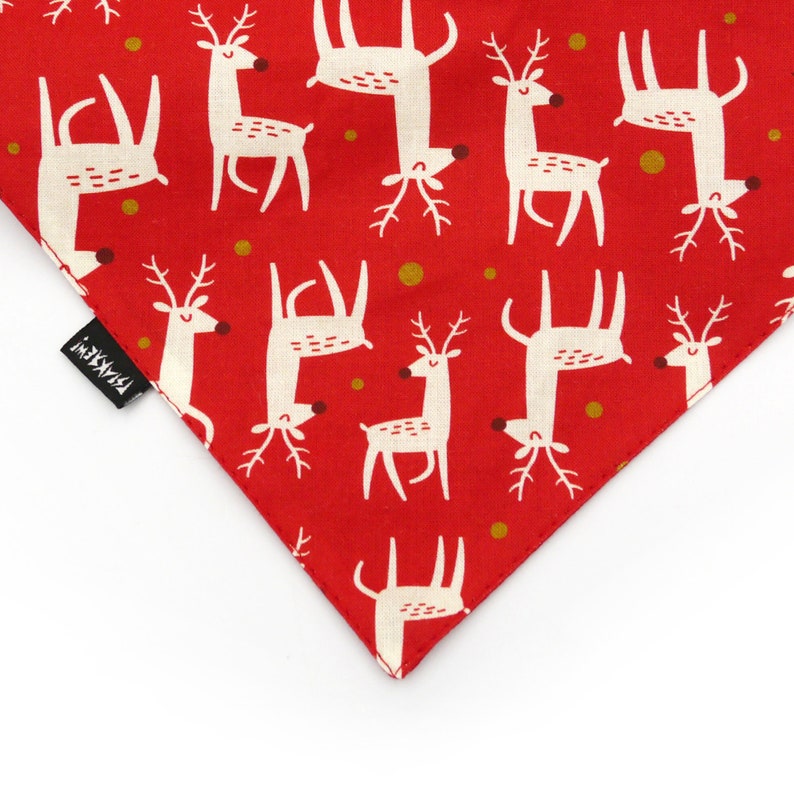May include: Red fabric with a white reindeer pattern. The fabric has gold dots and the text "Pawsitive" in black.