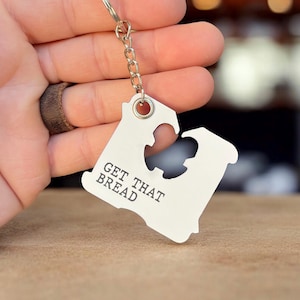 May include: A silver keychain shaped like a slice of bread with the text "GET THAT BREAD" on it.