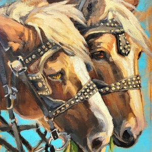 May include: Two brown horses with white markings on their faces are wearing leather bridles with metal accents. The horses are eating grass and have a blue background.
