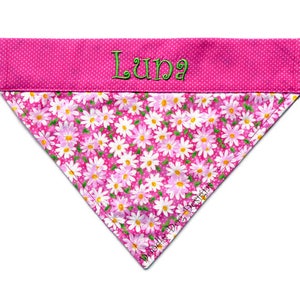 May include: Pink dog bandana with white daisy print and a pink polka dot trim. The bandana is personalized with the name "Luna" in green thread.