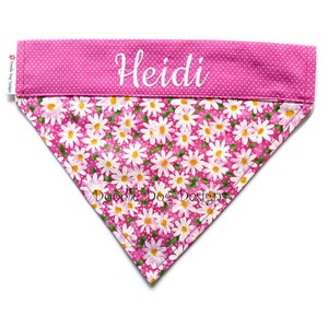 May include: Pink dog bandana with white daisy print and white polka dots. The bandana has the name "Heidi" embroidered on the top.