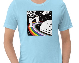 May include: A light blue t-shirt featuring a graphic of two astronauts dancing on a rainbow in space. The design includes a disco ball and a planet.
