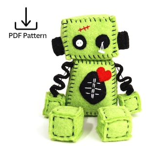 May include: A handmade green felt Frankenstein's monster doll with black stitched details, a red heart, and a stitched scar. The doll has black arms and cube-shaped feet. The text "PDF Pattern" is in the upper left corner.