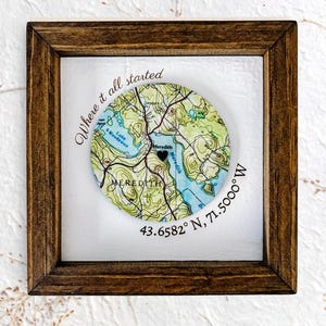 May include: A framed map print featuring a circular map of Meredith, with the text "Where it all started." The map is in shades of green and blue, with a black heart marking a location. Coordinates are displayed below the map.