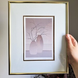 May include: A framed print of a still life featuring two vases with a branch of bare twigs in one of them. The print is in shades of gray and brown and has the text "La Branchie" and "Pierre Hirard" at the bottom.