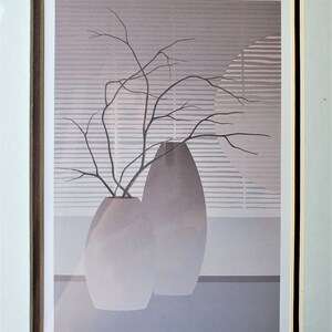 May include: A framed print of a minimalist still life featuring two gray ceramic vases with a branch of bare twigs in one of the vases. The background is a light gray with a pattern of horizontal lines. The print is signed "LA BRANCHE" and "PIERRE GIRARD".