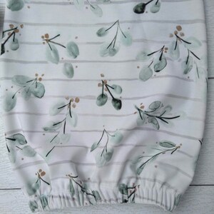 May include: White baby gown with a watercolor eucalyptus leaf pattern in shades of green and brown. The gown features horizontal gray stripes and an elasticated bottom hem. The fabric is soft and appears to be cotton.