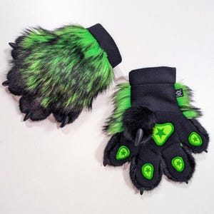 May include: A pair of furry paw gloves. The gloves are black with green accents and feature long, black claws. The paw pads are green with a star design. The wrist cuffs are black.