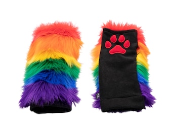May include: A pair of colorful fingerless gloves with a rainbow design. The gloves feature a black cuff and a red paw print on one glove. The faux fur is arranged in horizontal stripes of red, orange, yellow, green, blue, and purple.
