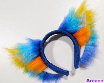 May include: A blue headband with faux fur ears in shades of yellow, orange, and blue. The headband is a dark blue color. The image also includes the word "Aroace" and a color palette.