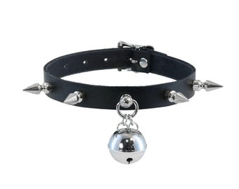 May include: Black leather choker necklace with silver-colored cone studs and a dangling silver bell. The choker has a buckle closure and a silver metal ring holding the bell.