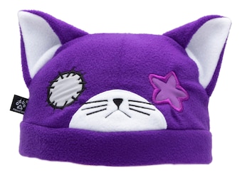 May include: Purple cat-eared beanie hat with white inner ears. The hat features a white face with embroidered whiskers and a black nose. A pink star and a white patch with black stitching are on the hat. The brand name "PAWSTAR" is on a black tag.