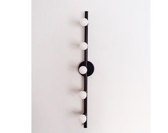 May include: A black metal light fixture with five white globe light bulbs. The fixture is mounted to a wall and has a circular base.