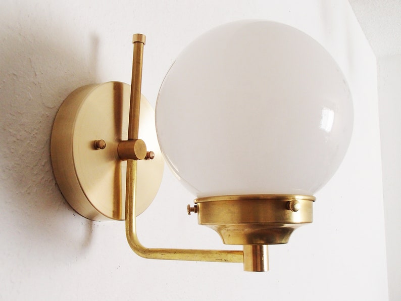 Peut inclure: Une applique murale en laiton avec un abat-jour en globe blanc. L'applique a un design simple et moderne et est parfaite pour ajouter une touche d'&eacute;l&eacute;gance &agrave; n'importe quelle pi&egrave;ce.