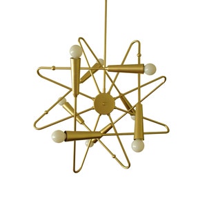 May include: A gold metal starburst chandelier with six light bulbs. The chandelier has a modern design and is perfect for a contemporary home.