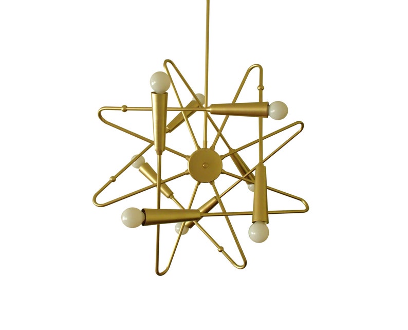 May include: A gold metal starburst chandelier with six light bulbs. The chandelier has a modern design and is perfect for a contemporary home.