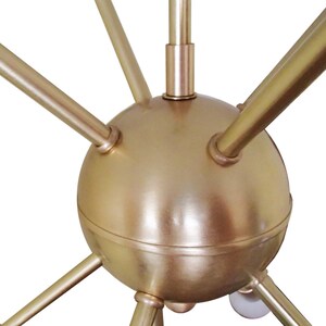 May include: A gold metal chandelier with a spherical center and six arms extending outward. The arms are all the same length and are evenly spaced around the center sphere.