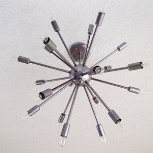 May include: A silver metal Sputnik style chandelier with multiple arms extending outward from a central sphere. Each arm has a light bulb at the end.