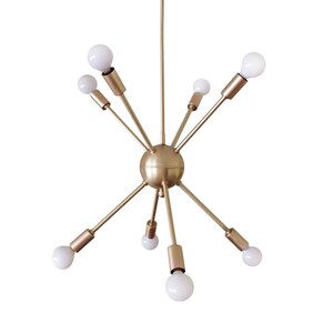 May include: A gold-toned, mid-century modern chandelier with eight light bulbs. The chandelier has a spherical center and six arms extending outward.