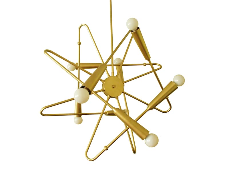 May include: A gold metal chandelier with six light bulbs. The chandelier has a geometric design with a starburst shape.