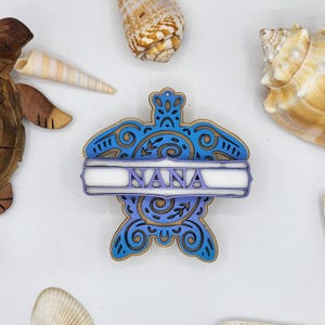 May include: A blue and purple wooden turtle ornament with a white banner that says "NANA".