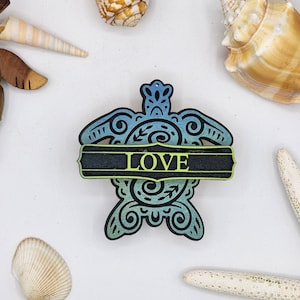 May include: A blue and green wooden turtle with intricate details and a black banner that says "LOVE" across the middle.
