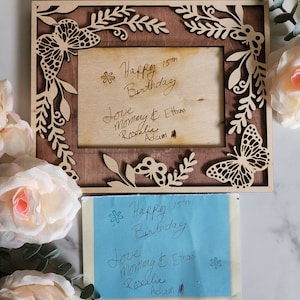 May include: A wooden picture frame with a butterfly design and a handwritten message that says "Happy 15th Birthday Love Mommy & Ethan Rosalie Adam".