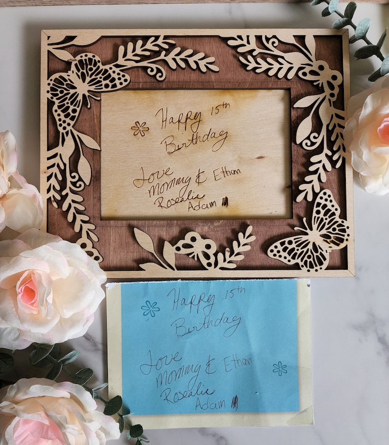 May include: A wooden picture frame with a butterfly design and a handwritten message that says "Happy 15th Birthday Love Mommy & Ethan Rosalie Adam".