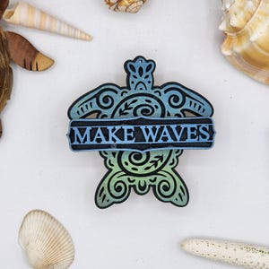 May include: A wooden turtle cutout with a blue and green gradient paint finish. The turtle has a decorative design and a banner that reads "MAKE WAVES".